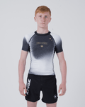 Kingz Galaxy Youth Rashguard Black White - Full Body Front View Teen Boy Athlete Short Sleeve Black White Ombre Galaxy Pattern Gold Star KINGZ Gold Text Crown Logo Black Shorts Kids BJJ [color:Black/Galaxy]
