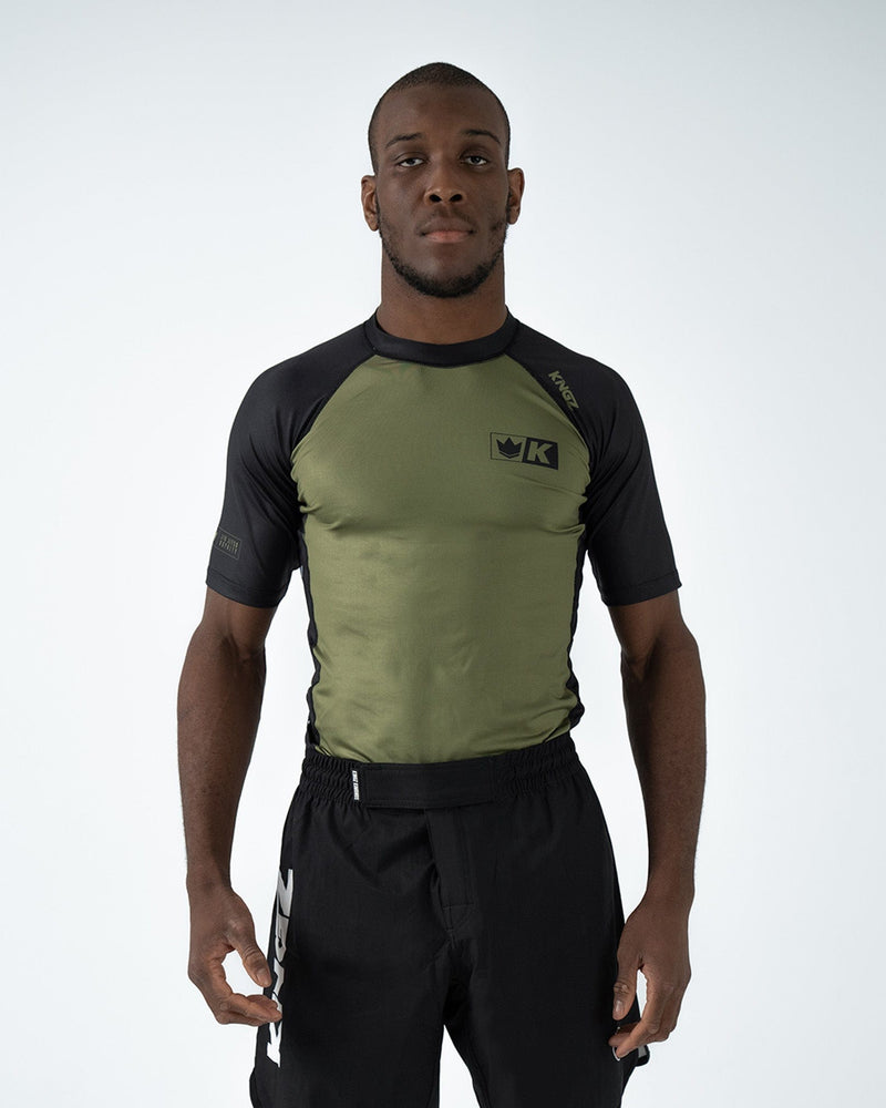 Kingz Krown S/S Rashguard Green - Full Body Front View Male Athlete Black Sleeves Olive Green Body K Crown Logo Left Chest KINGZ Text Right Shoulder Sleek Fit BJJ Grappling Rash Guard [color:Green]