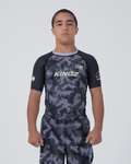 Kingz Viper Youth Rashguard Black Purple - Full Body Front View Teen Boy Athlete Short Sleeve Hexagonal Viper Scale Pattern KINGZ Text Green Crown Logo Purple Collar Matching Shorts Kids [color:Black/Purple Patterned]