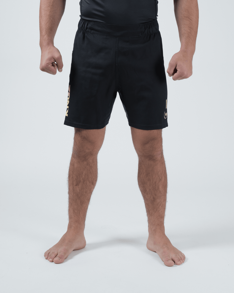 Kingz Player Special Limited Edition Shorts Black Gold - Full Body Front View Male Athlete All-Black KINGZ Gold Text Left Leg Gold Crown Badge Right Thigh Black Elastic Waistband Competition Cut Men's Grappling Shorts No-Gi BJJ Tainan Dalpra Signature Collection [color:Black]