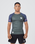 Kingz Draft Rashguard Storm Blue - Full Body Front View Male Athlete Short Sleeve Gray Charcoal Body Blue Raglan Sleeves White Crown Logo Pink KINGZ Labels Crown Badge Black Shorts [color:Storm Blue]