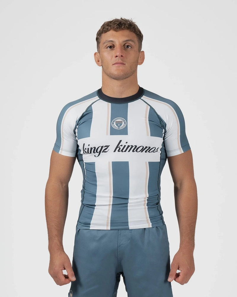 Kingz Vintage Futebol Rashguard Blue White Stripe - Full Body Front View Male Athlete Short Sleeve Retro Football Kit Vertical Stripes Kingz Kimonos Cursive Text Crest Badge [color:Green/Vintage]