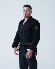 Kingz Legends Never Die Respect Gi in Black – front view on male model: black gi yellow crown badge left sleeve red patch waist white label
