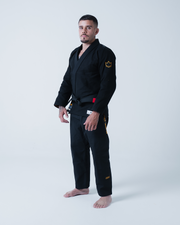 Kingz Legends Never Die Respect Gi in Black – full body front view on male model: black gi yellow crown badge sleeve red tab waist bold KINGZ text leg