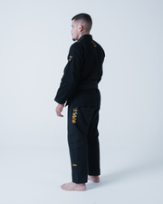 Kingz Legends Never Die Respect Gi in Black – back view on male model: black gi gold crown badge shoulder intricate text right leg durable fabric