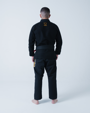 Kingz Legends Never Die Respect Gi in Black – full body back view on male model: yellow crown logo nape gold text right leg black fabric traditional