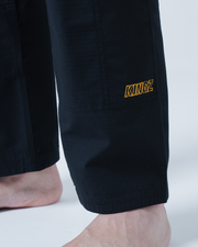 Kingz Legends Never Die Respect Gi in Black – close-up detail view: lower leg Kingz yellow logo embroidered black fabric
