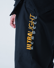 Kingz Legends Never Die Respect Gi in Black – close-up side view: embroidered ULTRALIGHT text vertical orange gray contrast durable fabric design