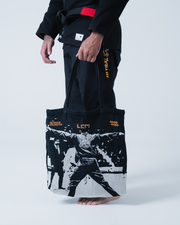 Kingz Legends Never Die Respect Gi in Black – side view on male model: black gi red belt orange text LLT7 graphic tote bag apparel