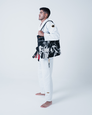 Kingz Legends Never Die Respect Gi in White – side view on male model: black crown badge sleeve bold ULTRALIGHT text pants KINGZ logo ankle black belt