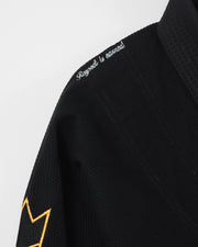 Kingz Legends Never Die Respect Youth Gi in Black – close-up detail view: embroidered "Respect is earned" white text shoulder yellow crown badge