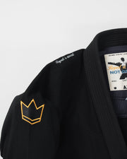 Kingz Legends Never Die Respect Youth Gi in Black – close-up detail view: embroidered crown badge yellow shoulder Respect Is Earned text inner label