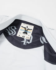 Kingz Legends Never Die Respect Youth Gi in White – close-up detail view: inner collar black pinstripe lining bold logo text patch