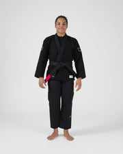 Kingz Legends Never Die Respect Women's Gi in Black – full body front view on female model: black gi gold crown shoulder patch black belt pink rank
