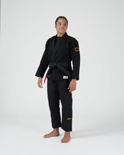 Kingz Legends Never Die Respect Women's Gi in Black – full body front view on female model: black gi yellow crown sleeve patch embroidered text pants