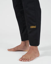 Kingz Legends Never Die Respect Women's Gi in Black – close-up detail view: lower leg yellow KINGZ embroidery black fabric women's apparel