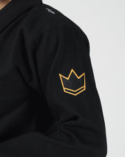 Kingz Legends Never Die Respect Women's Gi in Black – close-up detail view: embroidered gold crown badge left shoulder textured black fabric