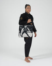 Kingz Legends Never Die Respect Women's Gi in Black – full body side view on female model: black gi gold crown logo sleeve embroidered patch graphic